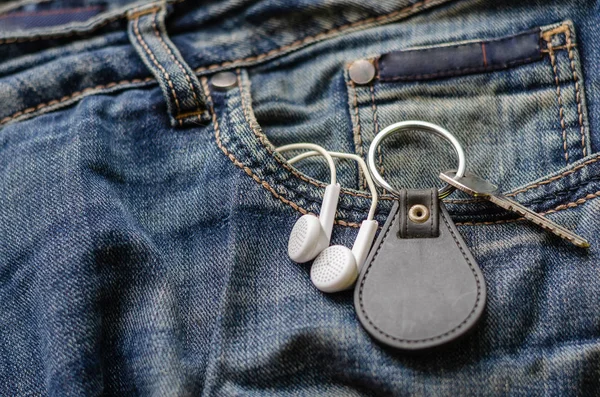 Nyckel med nyckelring och hörlurar i jeansficka. — Stockfoto