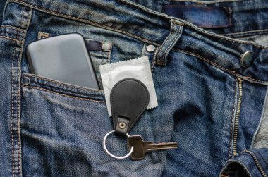 Anahtarlığı, telefonu ve kondomu olan mavi arka planda bir anahtar.. 