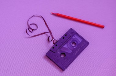 Masanın üzerinde eski siyah bir kaset ve kalem var.. 