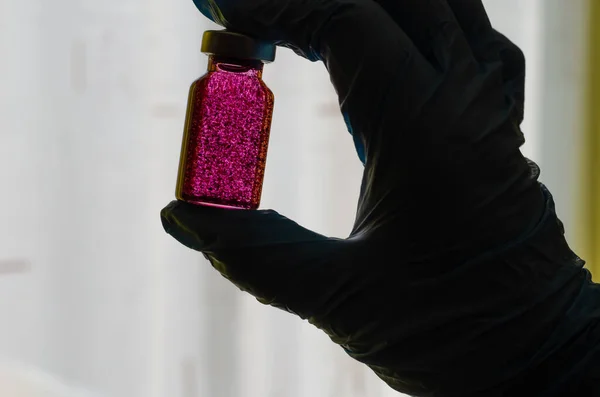 Silueta de una mano enguantada con una botella . —  Fotos de Stock