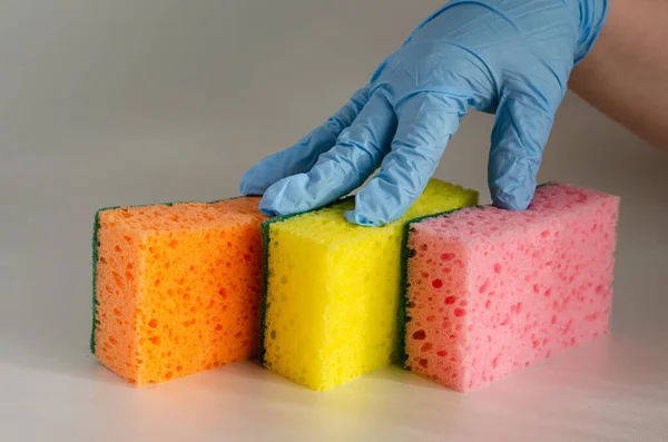 Three multi-colored kitchen sponges on the table.