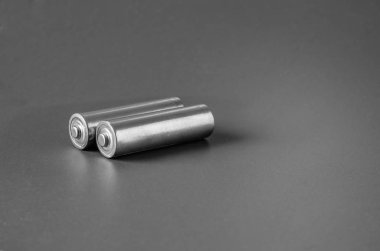 Gri arka planda iki silindirik pil..