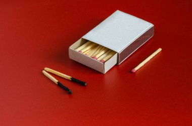 İki yanmış kibrit ve kırmızı arka planda yeni bir kibrit..