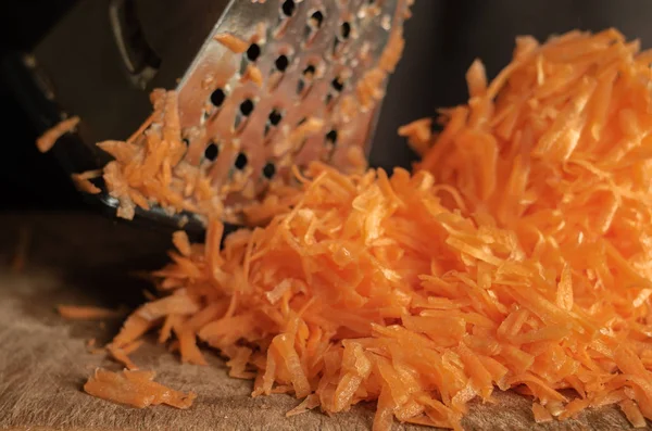 Grated carrots on a grater on the table. — Stock Photo, Image