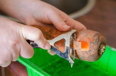 Bıçaklı bir kadın eli çiğ havuç soyar..