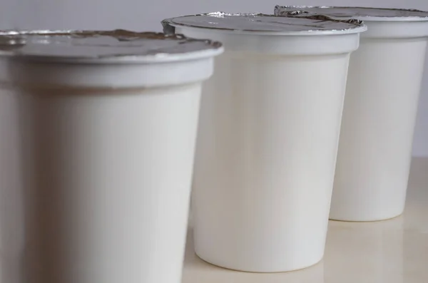 Three plastic containers with yogurt close-up. — Stock Photo, Image