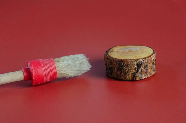 Paint brush and pine cut on a burgundy background. — Stock Photo, Image