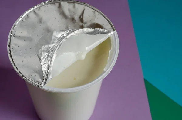 Un vaso de delicioso yogur con una tapa de lámina abierta . —  Fotos de Stock