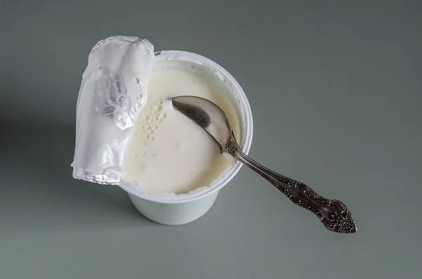 Cuchara inmersa en un delicioso yogur en un vaso de plástico . —  Fotos de Stock
