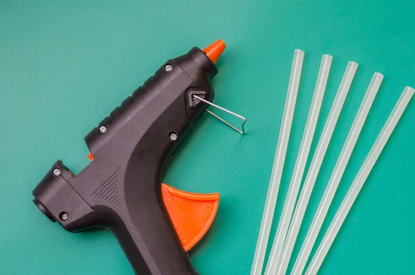 Electric Hot Glue Gun. Glue gun and five glue sticks on the table. Hand electric tool. View from above. Selective focus.