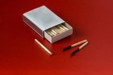 Kırmızı arka planda kibrit kutusu ve iki yanmış kibrit. Tam kibrit kutusunu aç. Konsept başka bir şans. Seçici odaklanma. Yakın plan..