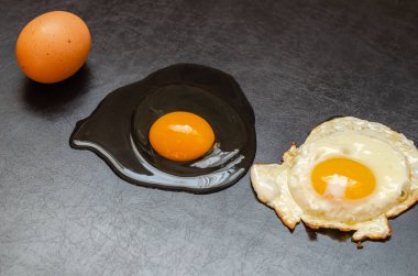 Tam tavuk yumurtası, çiğ ve sahanda yumurta. Siyah arka planda üç farklı ürün var. Yan görüş. Seçici odaklanma. Yakın plan.