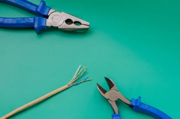 Diagonal cutting nippers, pliers and LAN cable. Nippers and pliers with blue handles. Handyman or DIY or industry. Close-up. Selective focus. Shooting from above at an angle.