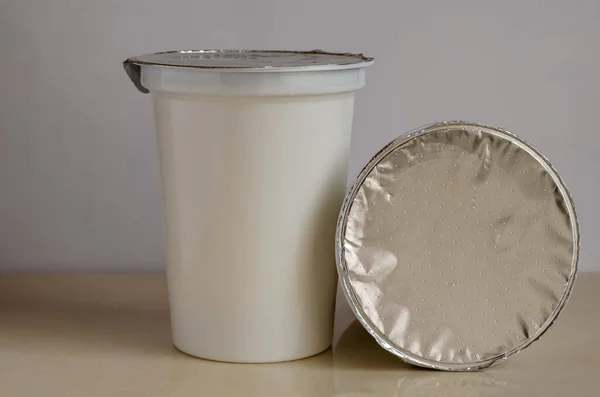 Plastikowe Pojemniki Jogurtem Jasnym Tle Dwie Szklanki Słodkiego Kwaśnego Mleka — Zdjęcie stockowe
