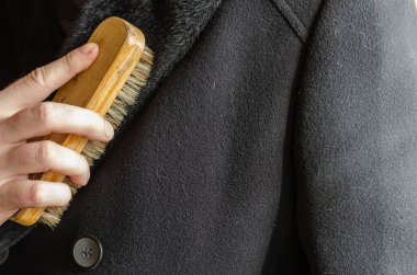 Erkek el fırçaları dış giysideki tozu ve kiri temizler. İş kıyafeti. Yakın plan. Seçici odak.