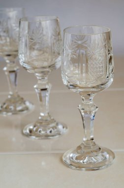 Bej arka planda klasik kristal şarap kadehleri. Bir sırada üç boş şarap kadehi. Yakın plan. Göz hizasında atış. Seçici odak.