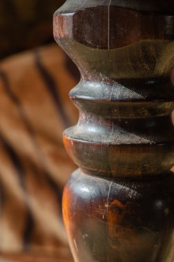 Yemek masasının büyük tahta bacağı. Güneşte oyulmuş eski bir bacak. Göz hizasında atış. Seçici odak.