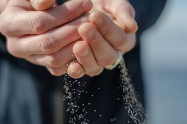Kum taneleri serpiştirilmiş iki avuç insan. Bir avuç dolusu dökülen deniz kumundan. Uzun zamandır beklenen tatilin keyfi. Göz hizasında atış. Kavramsal Odaklanmamış Arkaplan.