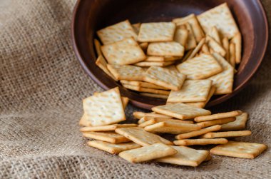 Çuval bezinde tuzlu kraker yığını. Kahverengi bir klozetten dökülmüş ikramlar. Ön plana odaklan. Hala sıcak yaşam renkleri. Yakın plan. Seçici odak.