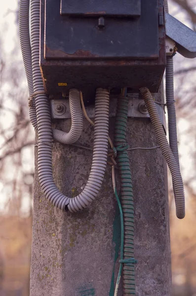 Concrete pillar with an old electrical panel. Rusty metal electrical panel on a street post. Outdated electrical equipment. Side view. Selective focus. Without people. City life.