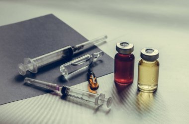 İlaçlar, şırıngalar, gri arka planda ampuller. İki ampul, iki şırınga ve iki ilaç şişesi. Göz hizasında atış. Yakın plan. Seçici odaklanma. İnsanlar olmadan.