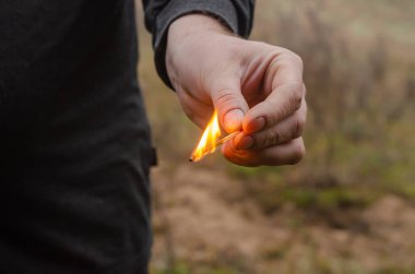 Açık havada yanan bir kibrit. Açık havada yanan bir kibrit. Yetişkin adam bir kibrit tutuyor. Kundaklama, orman yangınları, yangını dikkatsizce idare etme kavramı. Seçici odak.