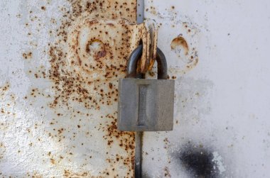 Asma kilitli paslı metal kapı. Kocaman asma kilidi olan parlak bir kapı. Özel mülk koruması. Göz hizasında atış. Seçici odaklanma. Yakın plan..