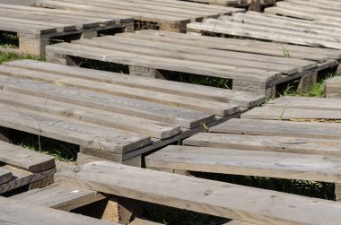 Yerde eski ahşap paletler var. Açık havada boş paletler. Lojistik deposu açıkta. Kargo deposu ve lojistik. Seçici odaklanma. İnsanlar olmadan.