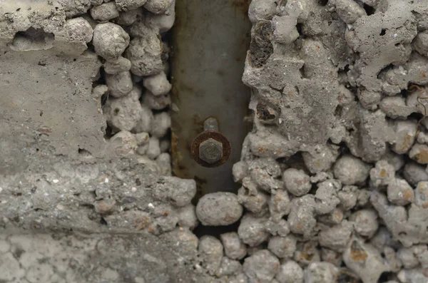 Metal beam with a bolt in the wall. Gray concrete wall with a rusty bolt. Expanded clay wall. Abstract multitask background. Selective focus. — Stock Image Metal Beam Bolt Wall Gray Concrete Wall Rusty Bolt Expanded Stock Photo