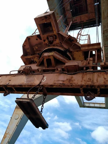 Old gantry crane against the sky. A heavy crane with heavy lifting hook and electromagnet on chains. Bottom view of the portal and the crane tunnel. Selective focus. Without people.