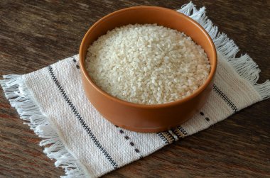 Kuru pirinç gevreğiyle kil kase. Kahverengi kase keten havlunun üstünde. Geleneksel yemek. Bir açıdan üstten bak. Seçici odaklanma. Yakın plan..