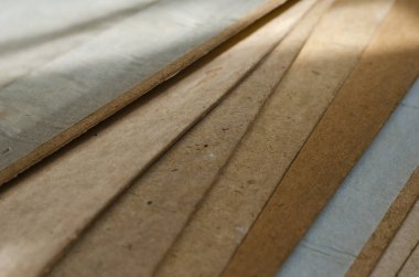 Güneşte eski karton çarşaflar. Tozlu inşaat karton yığını kapatılıyor. İnşaat malzemeleri. Göz hizasında atış. Seçici odaklanma. Yakın plan..