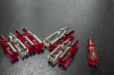 Koyu arkaplanda enjeksiyon için çok renkli ampuller. B1, B6 ve B12 vitaminli cam ampuller siyah bir masanın üzerinde bulunur. Sağlık hizmetleri. Seçici odaklanma. Yakın plan.