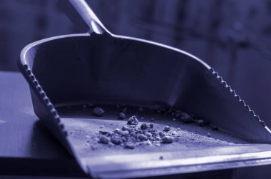 Gri kepçeyle çöpü kapatıyorlar. Kullanılmış faraş ve ev atığı. Soyut stil arkaplanı. Yan görüş. Seçici odaklanma. Renkli fotoğraf