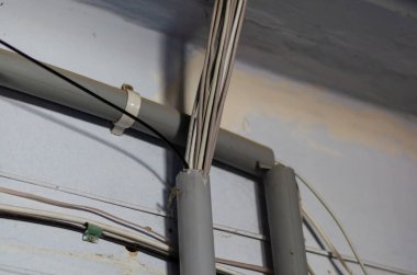 Bir LAN kablo grubu plastik boruların içine yönlendiriliyor. Bir apartmanın içindeki duvarda iletişim sistemi var. Konsept gereksinimlerin ve teknolojilerin ihlali. Seçici odak.