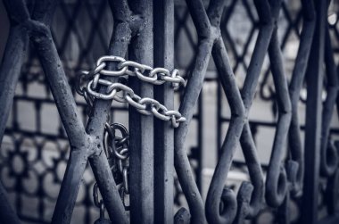 Metal bir kapıda zincir. Güçlü bir zincirli asma kilit ile büyük kapılar içeriden kapatılır. Yan görüş. Seçici odaklanma. Yakın çekim. İnsanlar olmadan.