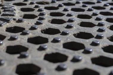 Altıgenlerin geometrik arkaplanı geri çekilen bir perspektifte. Tekrarlanan altıgen delikler ve paslı metaldeki çıkıntılar. Tasarım görevleri için çoklu görev arkaplanı. Göz hizasında atış. Seçici odak.