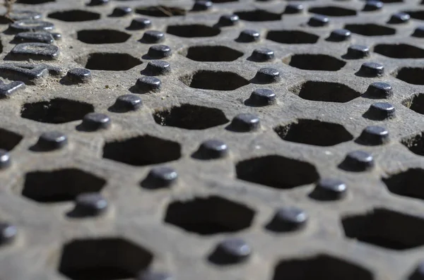 Altıgenlerin geometrik arkaplanı geri çekilen bir perspektifte. Tekrarlanan altıgen delikler ve paslı metaldeki çıkıntılar. Tasarım görevleri için çoklu görev arkaplanı. Göz hizasında atış. Seçici odak.