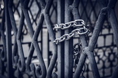 Metal bir kapıda zincir. Güçlü bir zincirli asma kilit ile büyük kapılar içeriden kapatılır. Yan görüş. Seçici odaklanma. Yakın çekim. İnsanlar olmadan.