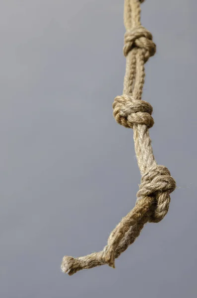 Jute rope hanging from above with knots. Rope with rough knots in a receding perspective. The concept of striving up for a better or achieving a goal. Selective focus. Close-up. Shooting from the bottom up.
