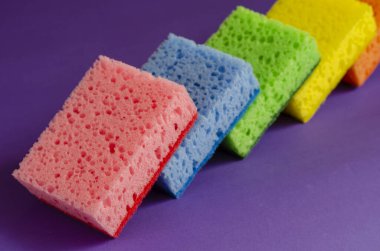 Mutfak süngeri eflatun arka planda. Çok renkli mutfak süngeri seti. Ev rutini ve ticari temizlik şirketi. Seçici odak.