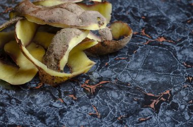 Patates soyuyordum. Masada patates olan bir yığın taze kabuk. Yemek pişirme süreci. Yiyecek atıkları. Seçici odak.