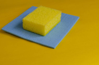 Mutfak süngeri ve sarı üzerine mavi temizlik peçetesi. Bulaşık ve temizlik için aksesuarlar. Ticari temizlik şirketi. Seçici odaklanma. Yakın plan..