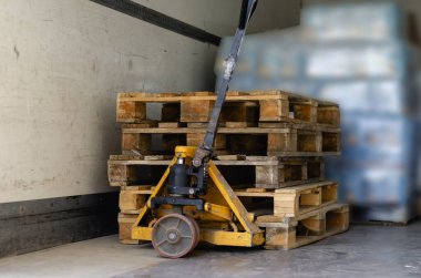 El arabası kamyonun içinde. Arka planda boş ahşap paletler, paletler ve eşyalar. Süpermarket için ürünleri indiriyorum. Ticaret ve lojistik. Paletlere odaklan. İnsanlar olmadan.