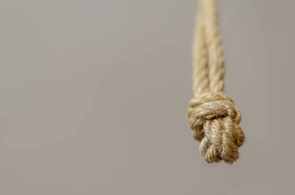 Jute rope hanging from above with knots. Rope with rough knots in a receding perspective. The concept of striving up for a better or achieving a goal. Selective focus. Close-up. Shooting from the bottom up.