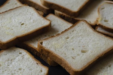 Sandviç ekmeği arka planı. Masanın üzerinde dikdörtgen ekmek yığını var. Açılı yan görüş. Yakın plan. Seçici odak.