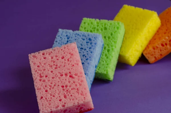 Kitchen sponges on a lilac background. Set of multi-colored kitchen sponges. Home routine and commercial cleaning company. Selective focus.