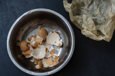 Metal bir kasede yumurta kabukları. Haşlanmış tavuk yumurtalarının kahverengi kabuğu paslanmaz çelik bir kasede. Yemek pişirme süreci. Yiyecek atıkları. Yukarıdan bak. Yakın plan. Seçici odak.