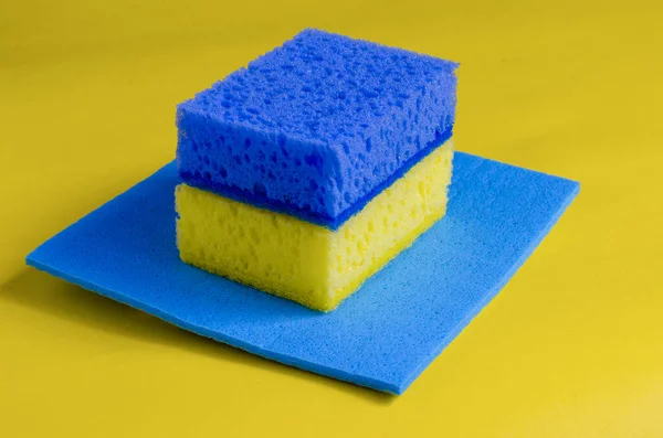 クリーニングナプキンの上に黄色と青のキッチンスポンジ クローズアップを洗浄するための明るいキッチン用品 掃除の楽しさ 選択的焦点 — ストック写真