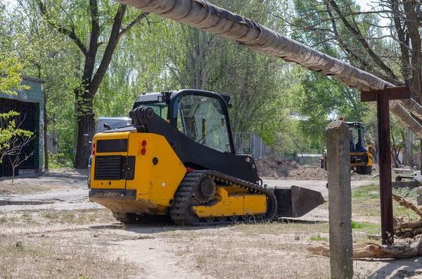 Lastik izleri olan küçük bir sürüngen kazıcısı. Sarı fren dümeni, bir şehir caddesinde toprak ile çalışan bir yük yükleyicisi. Endüstriyel makineler. Sanayi.